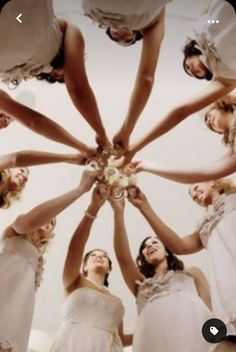 a group of bridesmaids standing in a circle holding their hands together to form a star