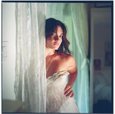 a woman in a white dress is looking out the window