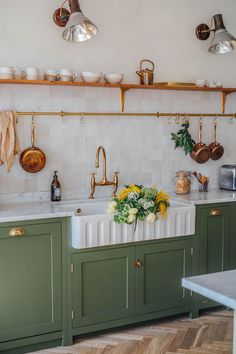 a kitchen with green cabinets and gold faucets on the wall above the sink