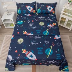 a bed with space themed sheets and pillow cases on top of the bedspread