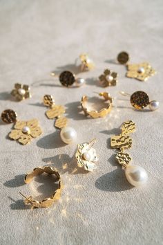 Embrace a touch of nature-inspired elegance with our Hammered Gold Abstract Flower Drop Earrings, each adorned with a lustrous pearl center. The hand-hammered gold petals catch and reflect light, creating a soft shimmer that adds warmth and sophistication to any look. These delicate yet eye-catching earrings are a versatile accessory, perfect for elevating both day and night ensembles with their timeless charm. Details Lightweight drop earrings Made of genuine white pearl Skillfully crafted in 1 Gold Pearl Earrings With Flower Shape For Party, Delicate Gold Petal Flower Earrings, Gold Flower Shaped Pearl Drop Earrings, Gold Pearl Earrings With Flower Shape, Gold Flower Earrings With Pearl Drop, Gold Flower Earrings With Pearl Charm, Gold Pearl Earrings With Flower Charm For Wedding, Gold Flower Earrings With Pearl Drop For Party, Gold Pearl Flower-shaped Earrings