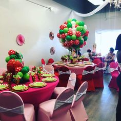 a room filled with tables covered in pink and green decorations