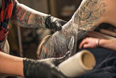 a man getting his tattoo done by another person with tattoos on their arm and leg