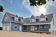 a large blue house sitting on top of a sandy beach next to the ocean with lots of windows