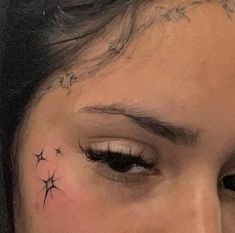 a close up of a person's face with stars on their forehead and behind her ear