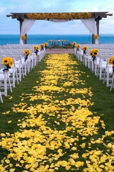 the aisle is decorated with yellow flowers and white chairs