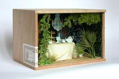 a miniature model of a bathtub in a wooden box with greenery around it