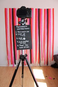 a tripod with a sign on it in front of a pink and red striped wall