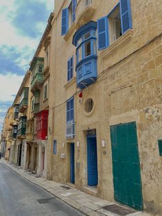 an old building with blue windows and shutters on the outside, next to a street