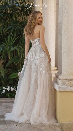 a woman in a wedding dress standing on the side of a building with her back to the camera