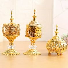 three golden vases sitting on top of a wooden table