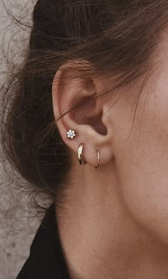 a close up of a person's ear wearing an earring with a flower on it