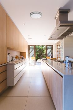 an empty kitchen with wooden cabinets and white counter tops is seen in this image from the hallway