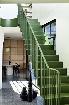 a green stair case next to a table and chairs