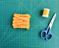 a pair of scissors and thread on a cutting board