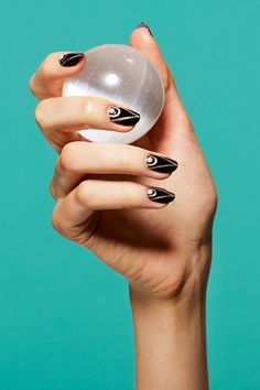 a woman's hand with black and white nail polish holding an object in her left hand