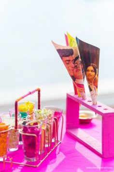 a table topped with cups filled with different types of drinks and pictures on top of it