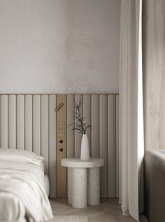 a white bed sitting next to a tall white vase on top of a table in a bedroom