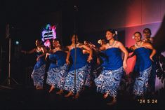 a group of women in blue dresses dancing on stage