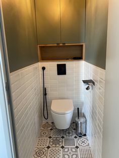 a white toilet sitting inside of a bathroom next to a wall mounted faucet