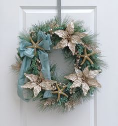 a christmas wreath hanging on a door with blue ribbon and gold poinsettis