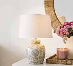 a table with a lamp, vase and flowers on it