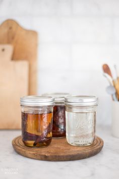 three jars filled with food sitting on top of a wooden tray