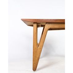 a wooden table with two legs and a curved edge on the top, against a white background