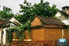 an old brick building with ivy growing on it's roof and some trees in the background