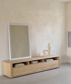 a white vase sitting on top of a wooden cabinet next to a mirror and shelf