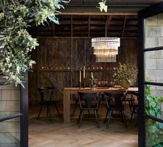 an open door leading to a dining room with wooden floors and walls covered in greenery