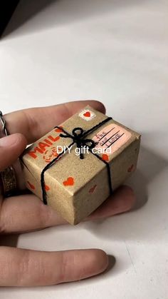 a hand holding a small gift wrapped in brown paper