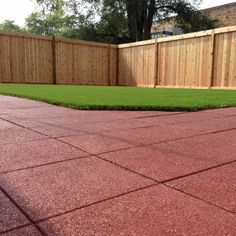 an empty backyard with grass in the middle and a wooden fence behind it on a sunny day