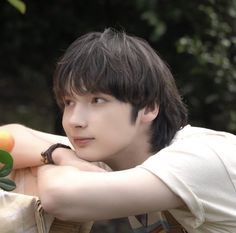 a young man leaning on a table with an orange in his hand