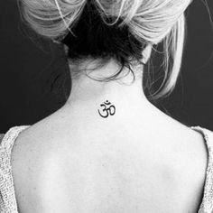 the back of a woman's neck with an om symbol tattoo on it