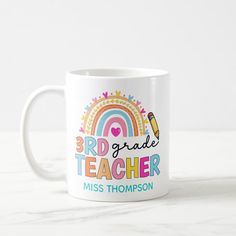 a white coffee mug with the words 3rd grade teacher miss thompson on it and a rainbow in the background