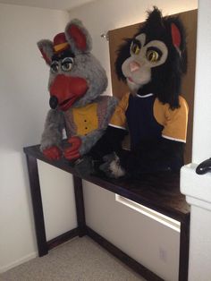 two stuffed animals sitting on top of a wooden shelf next to each other in a room