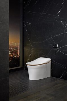 a modern bathroom with black marble walls and flooring, along with a white toilet