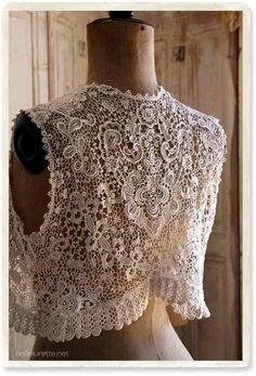 the back of a dress on a mannequin with an intricate lace pattern and black flower