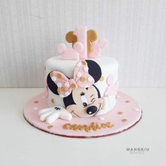 a pink and white cake with minnie mouse on top