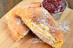 ham and cheese sandwich cut in half on a cutting board next to a bowl of jelly