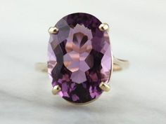 This simple vintage cocktail ring features a super deep purple Amethyst in the center, one that really flashes and flickers with vibrant violet reflections! Set into a lovely vintage mounting that is utter simplicity, this vintage ring is a beautiful addition to anyone s collection! Metal: 14K Yellow Gold Gem: Amethyst 10.04 Carats Gem Measurements: 12.2 x 17.3 mm, Oval Ring Size: 5.75 Marks: "@ RSA 14K" Stamped on the inside band Timeless Oval Purple Amethyst Ring, Timeless Purple Oval Amethyst Ring, Classic Purple Amethyst Ring, Classic Purple Solitaire Ring, Classic Oval Purple Amethyst Ring, Classic Purple Rings For Formal Occasions, Vintage Purple Solitaire Ring, Yellow Gold Sapphire Ring, Yellow Gold Cocktail Ring