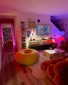 a living room filled with lots of furniture and colorful lights on the wall behind it