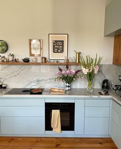 a kitchen with white cabinets and marble counter tops, flowers on the oven door shelf