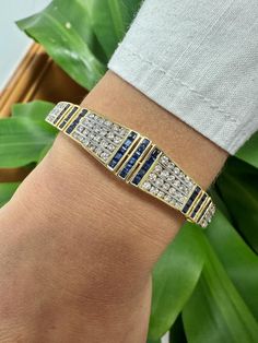 5.09 carat total blue sapphire and white diamond bangle bracelet. Adorned with 40 baguette cut natural blue sapphires (2.24 cttw) and 84 round cut white diamonds (2.85 cttw). The gemstones are all bezel/channel set. The face width of the bangle is 12.2mm and the bangle is all set in 18k yellow gold with a smooth, polished finish. This piece follows a mix of art deco symmetry with an Egyptian revival color pattern.  Details:  ✔ Item type: Bangle ✔ Metal: 18k Yellow Gold ✔ Diameter: 2.3 inch ✔ Wei Blue Diamond Hand-set Bracelet, Blue Diamond Bangle Bracelet Fine Jewelry, Blue Diamond Bangle Fine Jewelry Bracelet, Fine Jewelry Blue Round Bangle, Blue Diamond Bangle Bracelet In Fine Jewelry Style, Blue Diamond Bangle Jewelry, Blue Diamond Bangle Bracelet With Accents, Luxury Blue Gemstone Bangle, Blue Bangle Tennis Bracelet For Formal Occasions