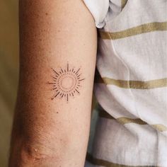 a woman's arm with a small sun tattoo on the left side of her arm