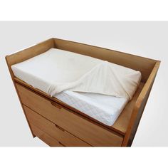 a wooden dresser with a mattress in it and white sheets on the bottom drawer area