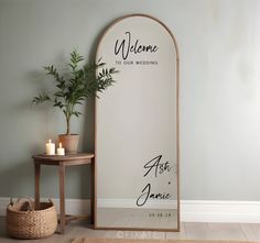 a welcome sign is next to a table with a potted plant and candle on it