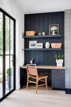 a home office with black painted walls and wooden desk, potted plants on the shelves