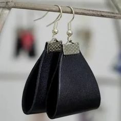 two black leather earrings hanging from a metal hook